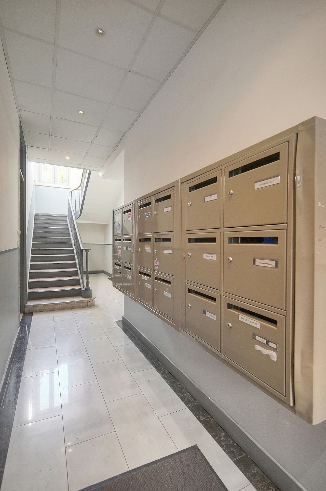 A hallway with a staircase leading to an upper floor, lined with metal filing cabinets on the right.