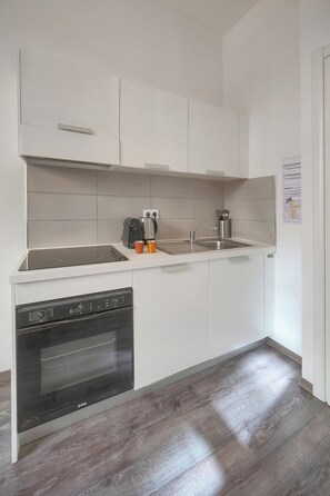 A modern kitchen with white cabinets, a built-in oven, and a stainless steel sink. - 15239747 FRGK 1-Bedroom Design 300m Palais & Beach Apartment (Cannes)