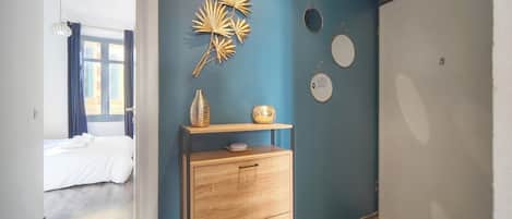 A bedroom with a bed, a wooden dresser, a wall with decorative items, and a window with curtains.