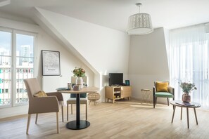 Un salon moderne comprenant une table à manger, des chaises, un téléviseur et une vue sur la ville.