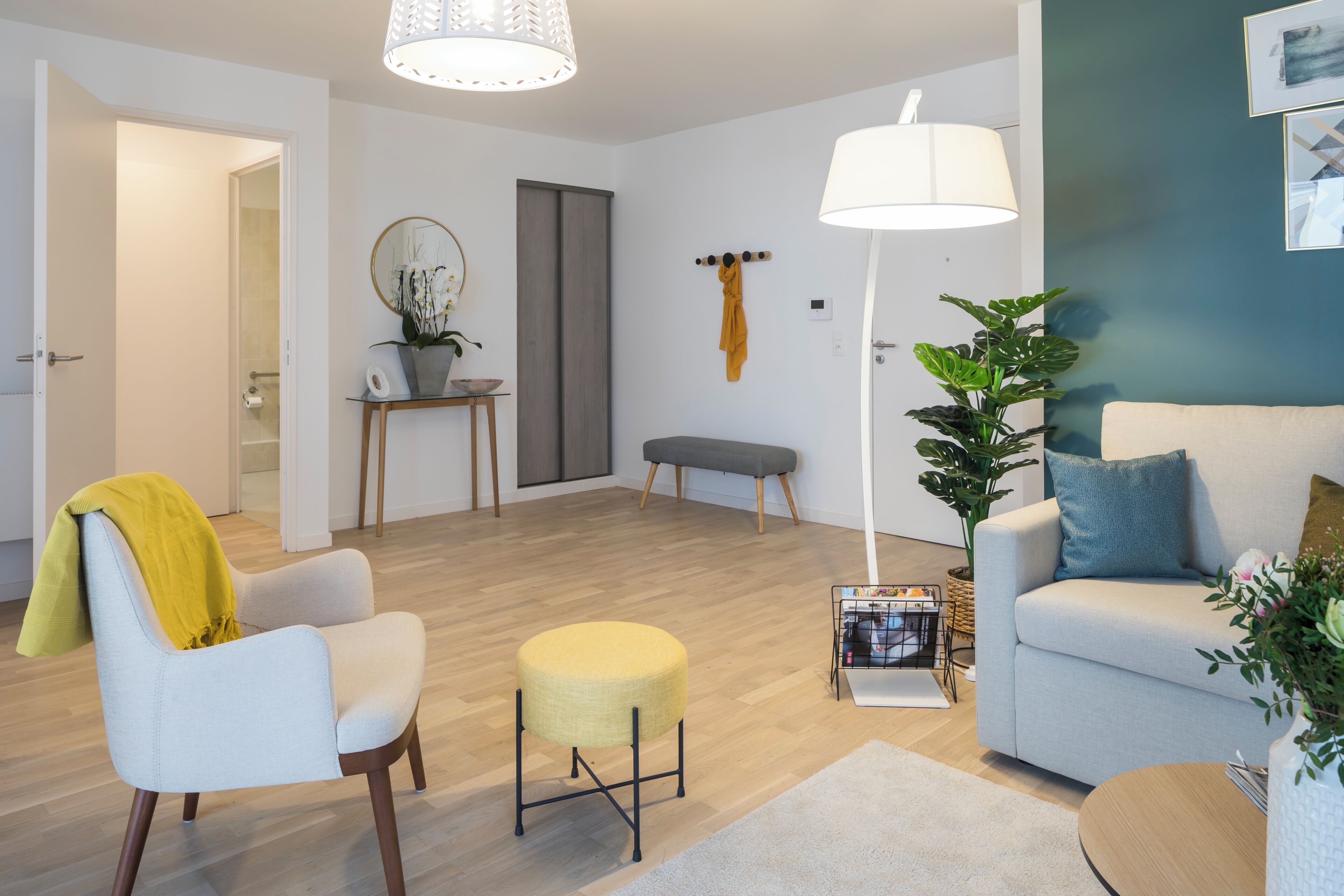 Una sala de estar moderna con sofá, sillón, banqueta y lámpara.