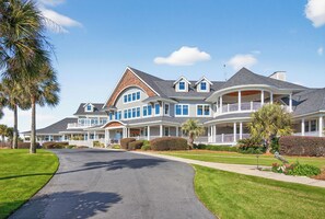 A large, multi-story house with a curved driveway, multiple balconies, and a well-maintained lawn. - Deer Run Hideaway - Game Room (Johns Island)