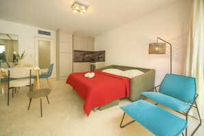 A hotel room with a bed, a desk, chairs, a mirror, and a lamp. - One-bedroom apartment in Nice, France (Niza)