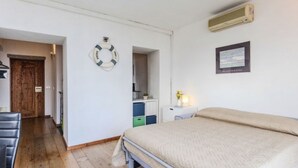 Ein Schlafzimmer mit Bett, Schreibtisch, Stuhl, Kleiderschrank und einer Tür.