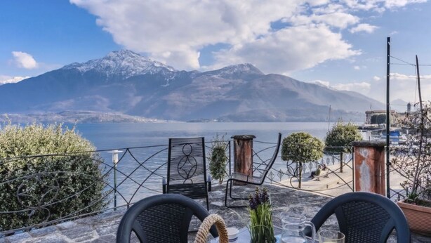 Ein Tisch mit Obst und Getränken mit Blick auf einen See und Berge.