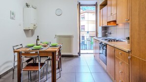 A kitchen with wooden cabinets, a stove, and a dining table with chairs. - Cozy Holiday Home by Interhome (Dongo)