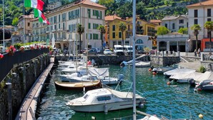 A marina with boats docked, surrounded by buildings with balconies and a mountainous backdrop. - Casa Luvit by Interhome (Menaggio)