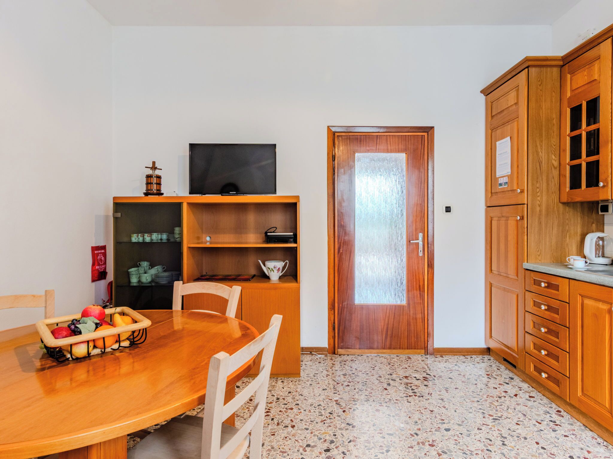Una cucina compatta con un tavolo da pranzo, sedie, un frigorifero e mobili in legno.