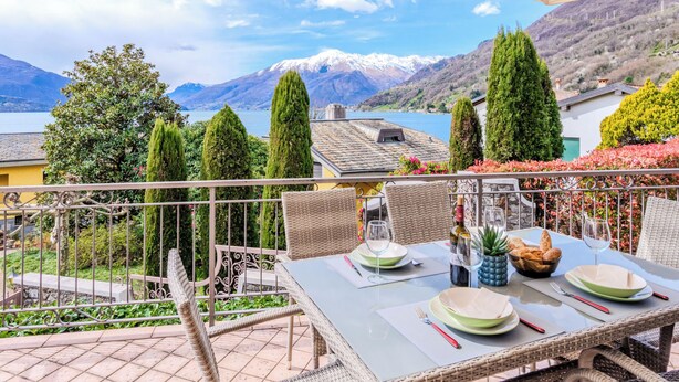 A table set outdoors with a mountain view, a dining area with chairs, and a railing. - Onda Blu by Interhome (Gera Lario)