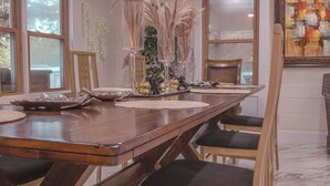 Una mesa de comedor de madera con diseño moderno, rodeada de sillas con asientos acolchados.