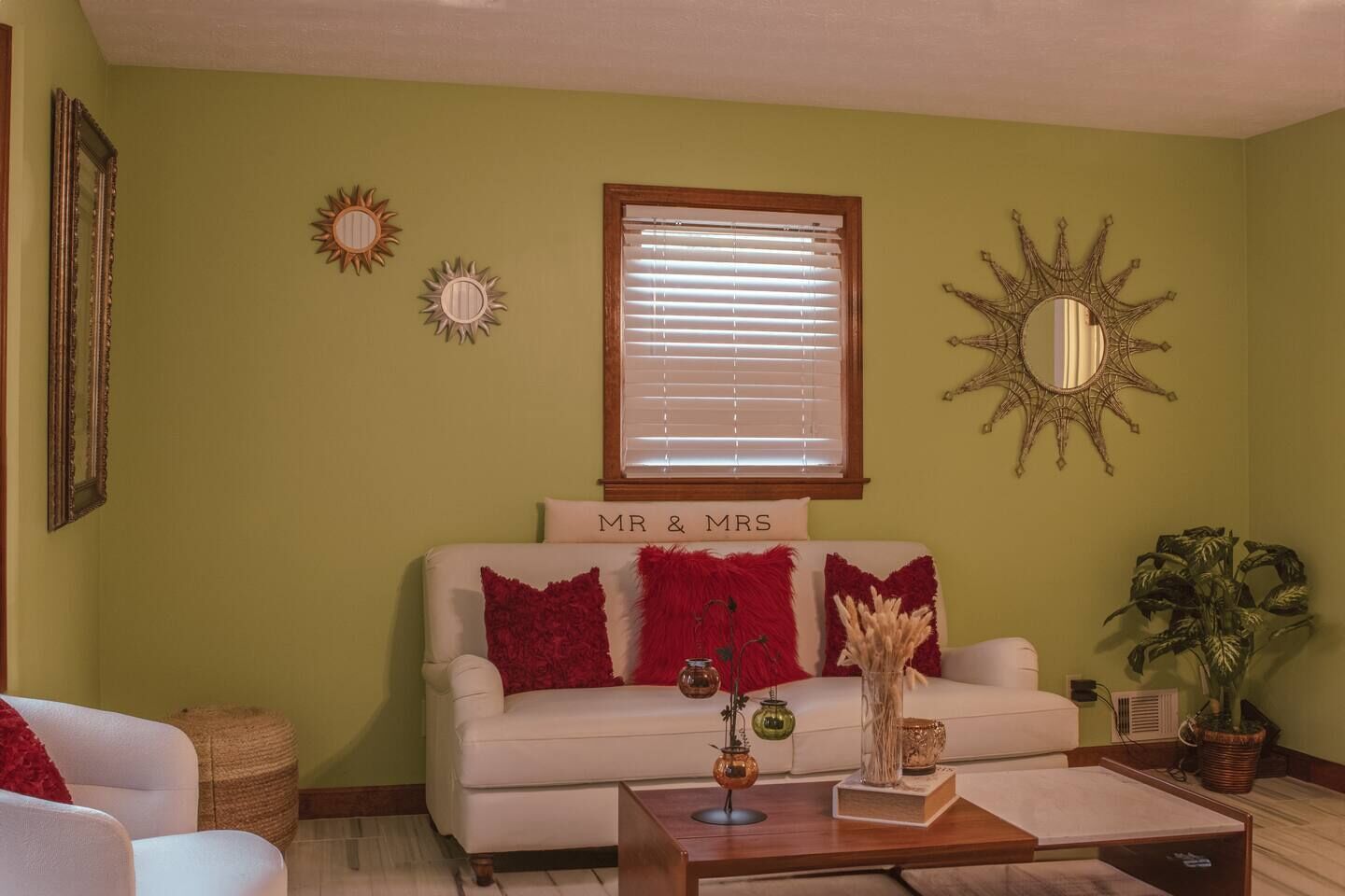 A living room with a sofa, a coffee table, decorative pillows, a sign reading 'MR & MRS', and wall art.