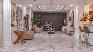 Amplia sala de estar con piso de mármol, una mesa de centro y diferentes disposiciones de asientos.