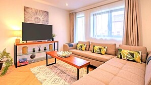A living room with a sofa, TV, coffee table, and a window with curtains. - HH 120m2 | Fast wi-fi | Work | Holiday |BBQ | Pet (Tonbridge)