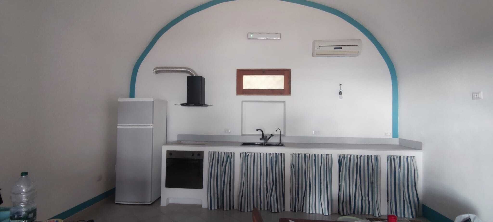Una cocina compacta con refrigerador, pileta y ventana.