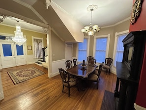 A dining area with a wooden table and chairs, a chandelier, and a fireplace. - Historic Belle Maison: Billiards Room, Fire Pit & Magnolia Charm (Magnolia)
