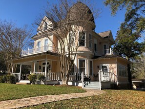 A two-story house with a wrap-around porch, a turret, and a large front yard. - Historic Belle Maison: Billiards Room, Fire Pit & Magnolia Charm (Magnolia)