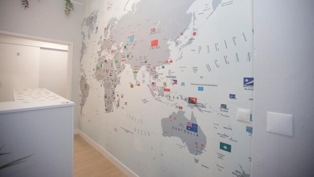 A wall with a world map featuring country flags. - Aerostay Hostel (Maia)