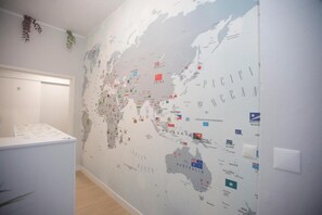 A wall with a world map featuring country flags. - Aerostay Hostel (Maia)