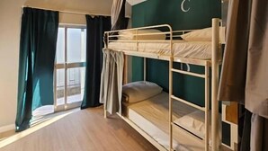 A bunk bed room with a window, curtains, and a ceiling light. - Aerostay Hostel (Maia)