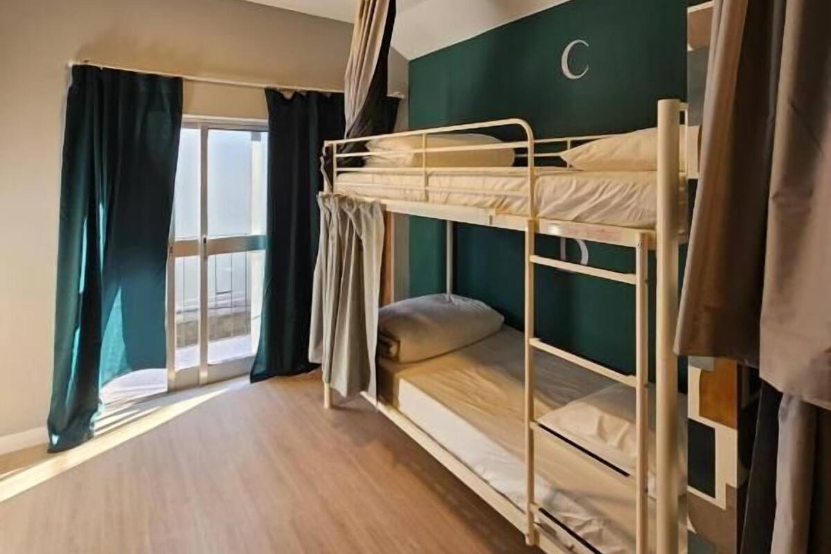 A bunk bed room with a window, curtains, and a ceiling light.