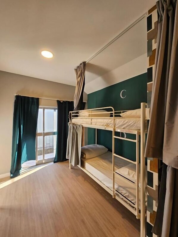 A bunk bed room with a window, curtains, and a ceiling light. - Aerostay Hostel (Maia)
