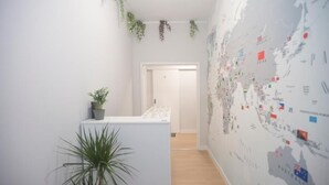A hallway with a map wall, a plant, and a door leading to another room. - Aerostay Hostel (Maia)