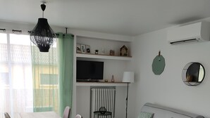 A modern living space with a dining table, chairs, a sofa, a TV, and a radiator. - Air-conditioned apartment with balcony, wifi, near ramparts (Avignon)