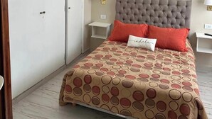 Une chambre à coucher comprenant un lit, deux tables de chevet, une commode, une armoire et une lampe fixée au mur.