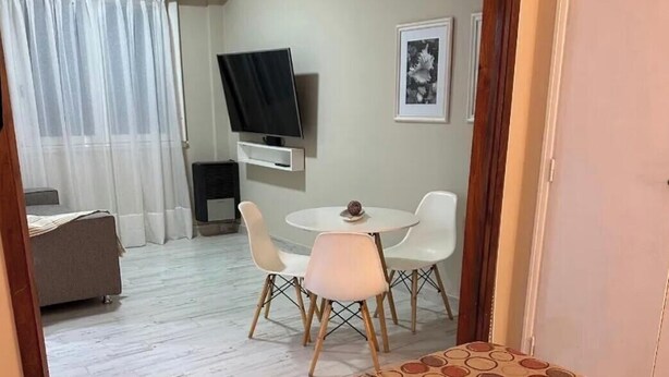 Une chambre d’hôtel avec un lit, une télévision, une petite table avec des chaises, un canapé et un rideau.