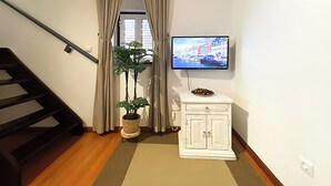 Un escalier, une plante en pot, un téléviseur et une petite armoire dans une pièce.