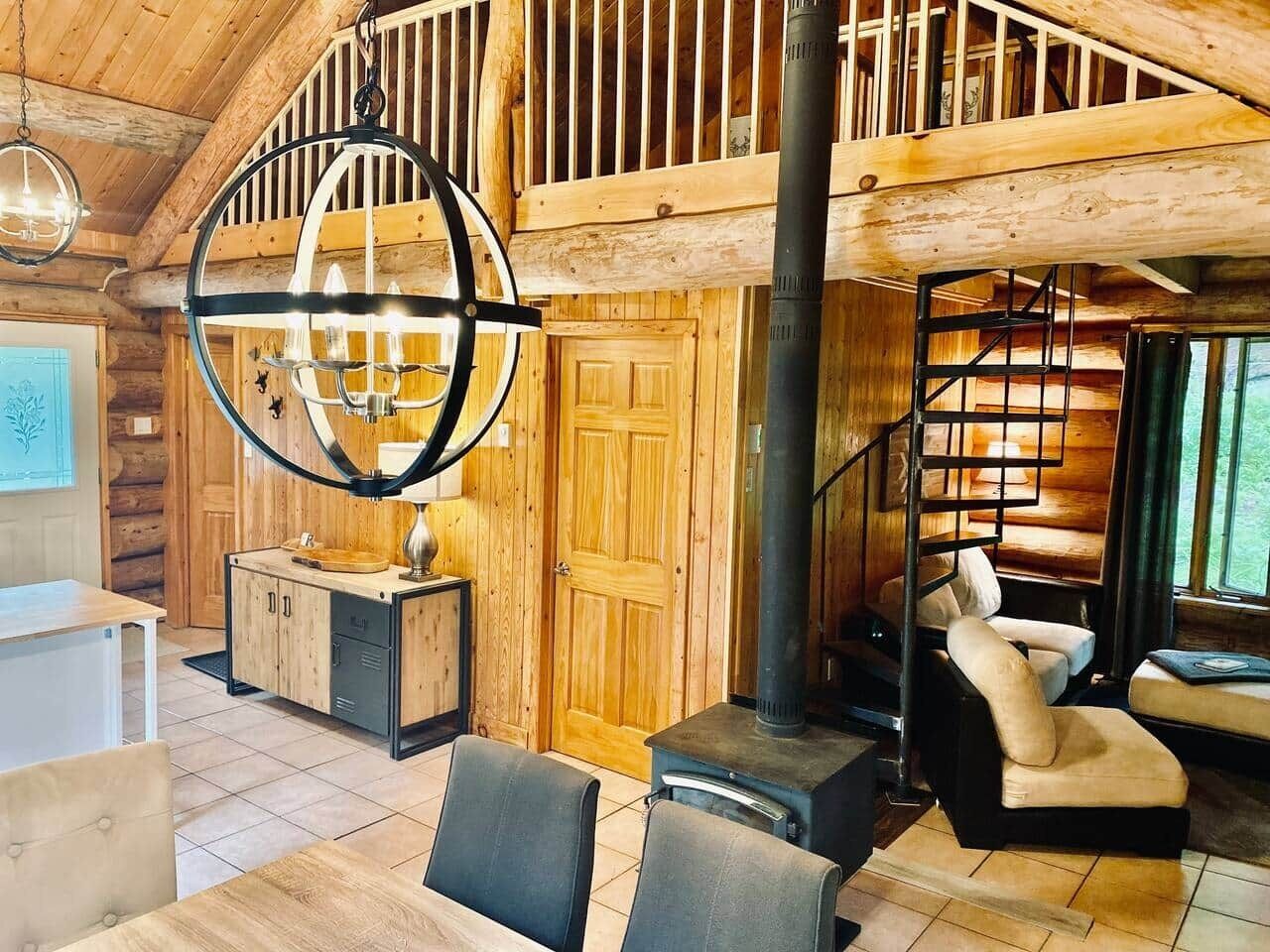 Ein Holzblockhaus-Interieur mit Essbereich, Treppe und großem Fenster.