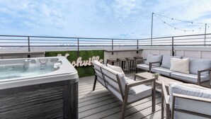 En takterrass med ett bubbelbad, utomhusmöbler och utsikt över stadens silhuett.