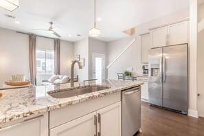Eine moderne Küche mit Edelstahlkühlschrank, Granit Arbeitsplatte und integriertem Geschirrspüler.