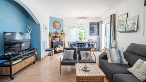 Un salon avec un téléviseur, un canapé et une table basse. Il y a également un coin repas avec une table et des chaises.