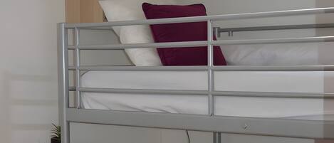 A bunk bed with a shelf above and a small table below.