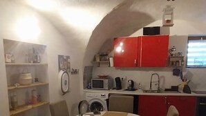Een compacte keuken met een eethoek, met een rode kast, een magnetron en een spoelbak.