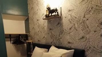 A bedroom with a bed, pillows, a nightstand, a lamp, and a wall with a floral pattern.