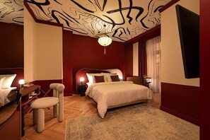 Un dormitorio con una cama grande, un rascador para gatos, un escritorio y un techo con diseños abstractos.