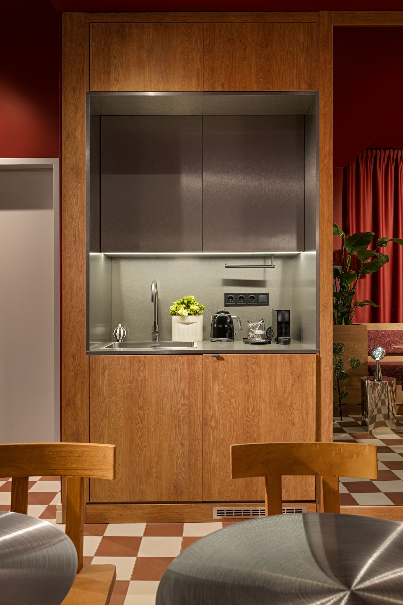 Una cocina compacta con gabinetes de madera, un lavamanos de acero inoxidable y electrodomésticos modernos.