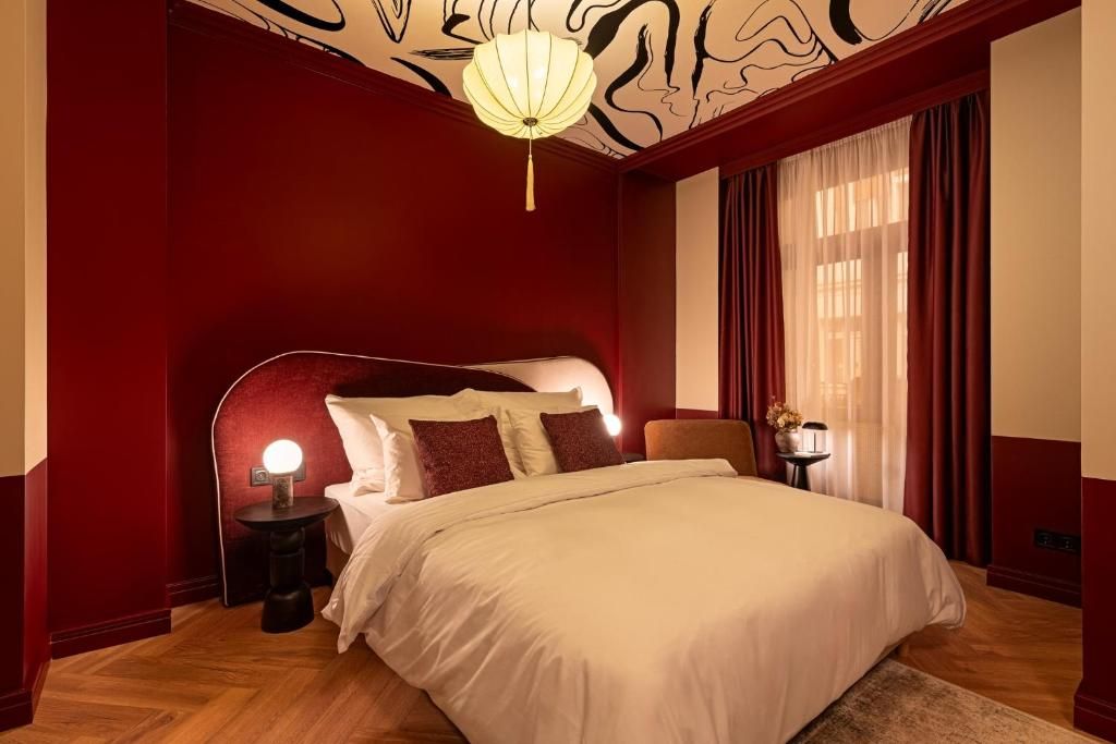 Une chambre d’hôtel avec un grand lit, une table de chevet avec une lampe et un luminaire décoratif au plafond.