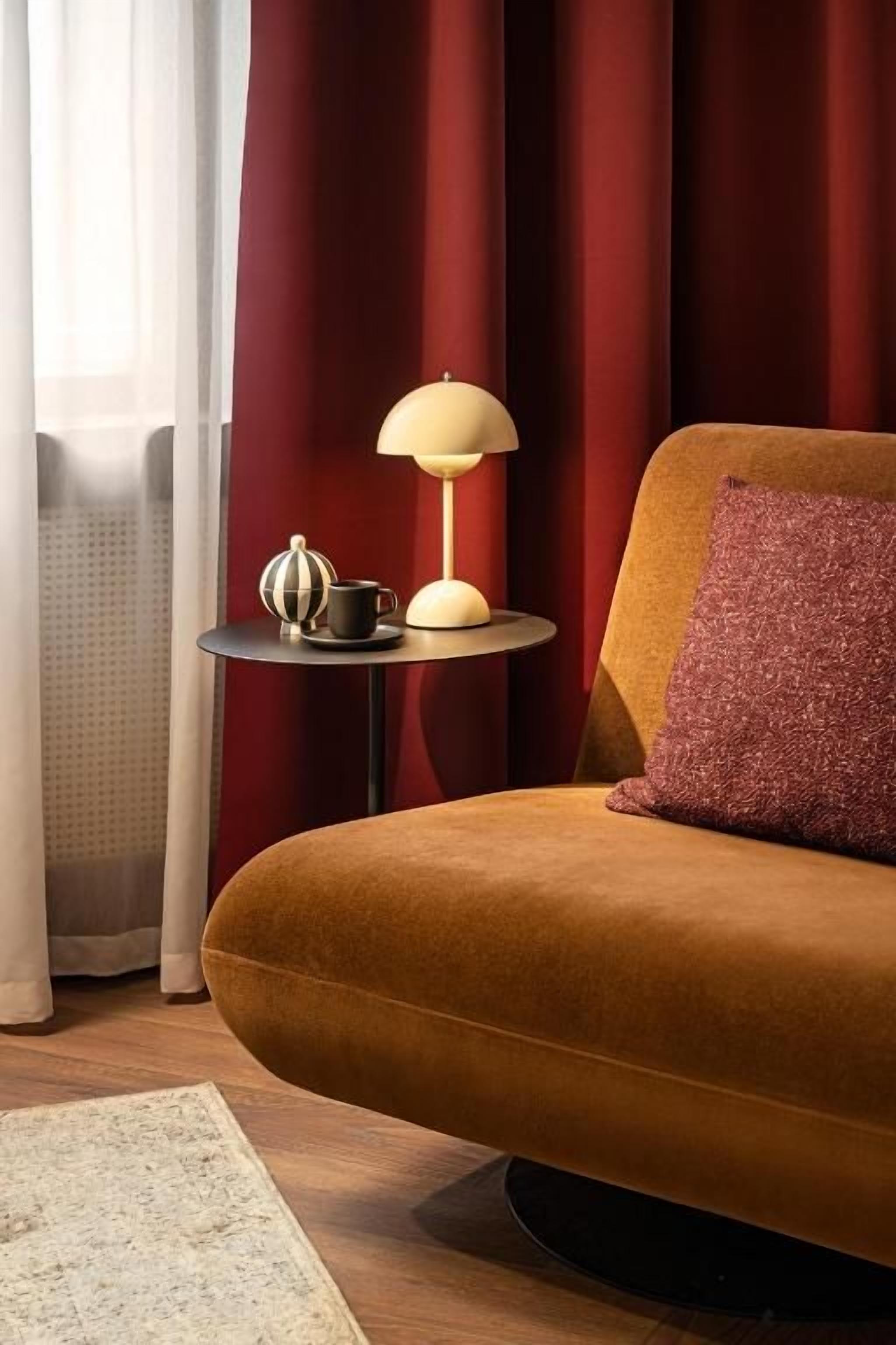 Una habitación con un sofá, una mesita con una lámpara y un objeto decorativo.