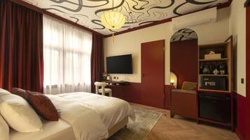 Habitación de hotel con una cama grande, un escritorio, televisor de pantalla plana, armario y minibar.