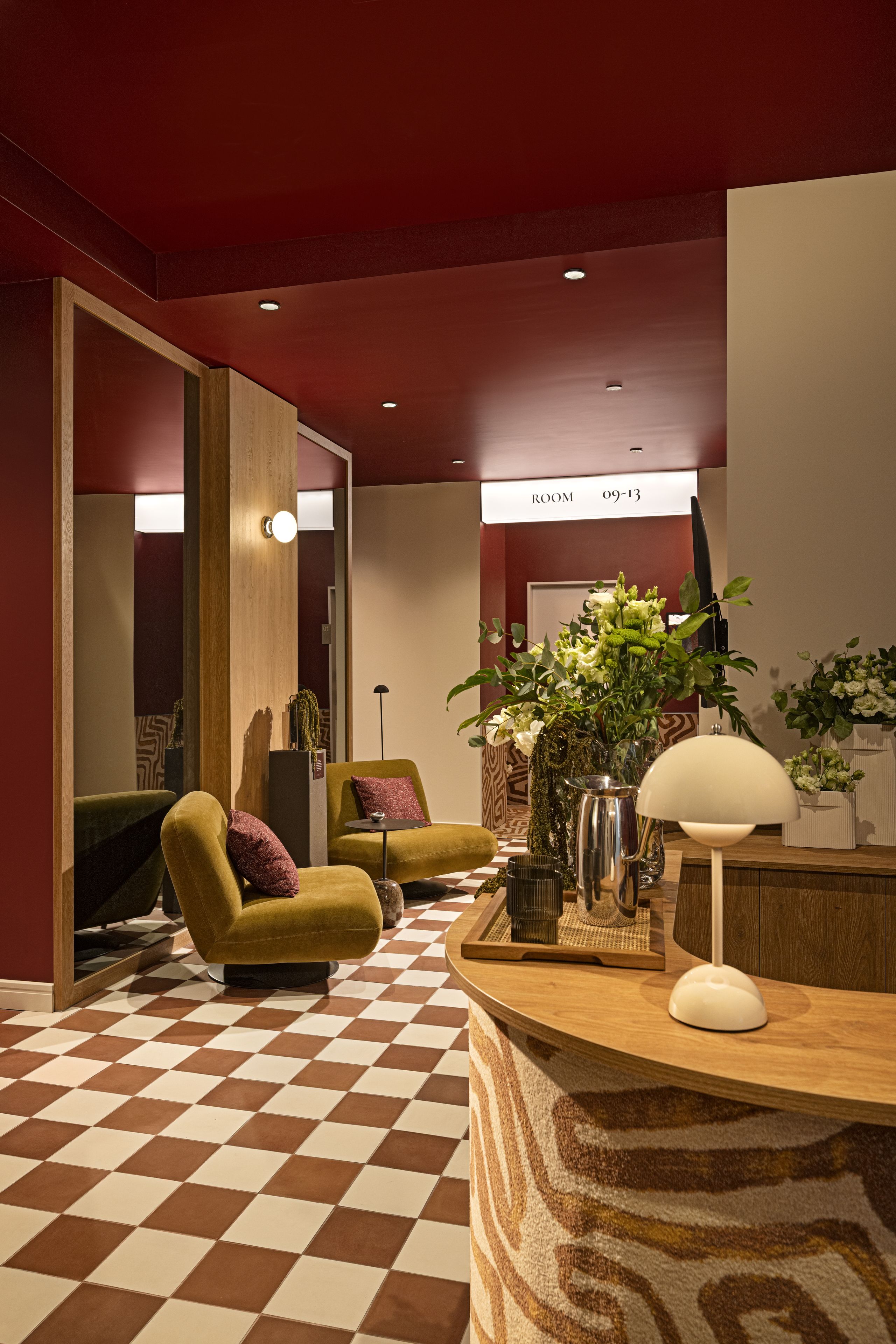 Un vestíbulo de hotel con suelo de cuadros, una recepción, un sofá y un espejo.