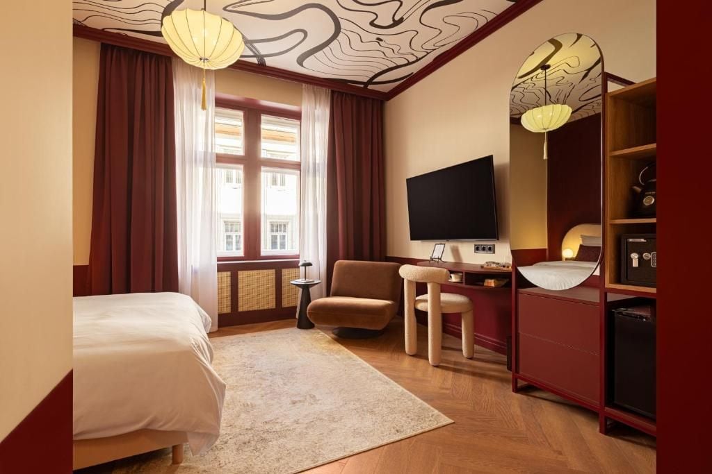Een hotelkamer met een bed, een bureau met een computer, een stoel, een televisie en een boekenkast.