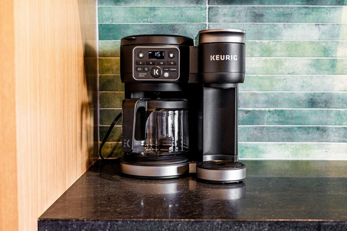A Keurig coffee maker with a glass carafe and a K-cup pod on a kitchen counter.