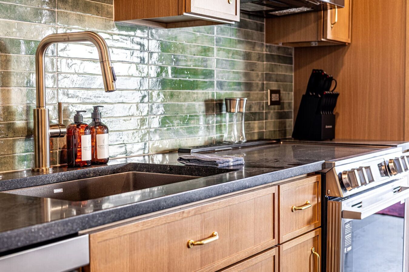 A kitchen with a stainless steel sink, wooden cabinets, and a gas stove.