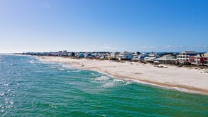 Uma área costeira com casas à beira-mar, uma praia arenosa e o oceano.