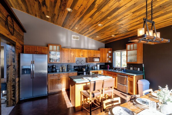 Eine moderne Küche mit Holzausstattung, einem Edelstahlkühlschrank und einem Essbereich mit Tisch und Stühlen.