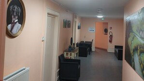 A hallway with a radiator, a framed picture, a table with chairs, and a painting on the wall. - Les Marais Comtois (Saône)