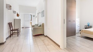 En hall som leder till ett sovrum med en säng, en stol, en soffa och en garderob.